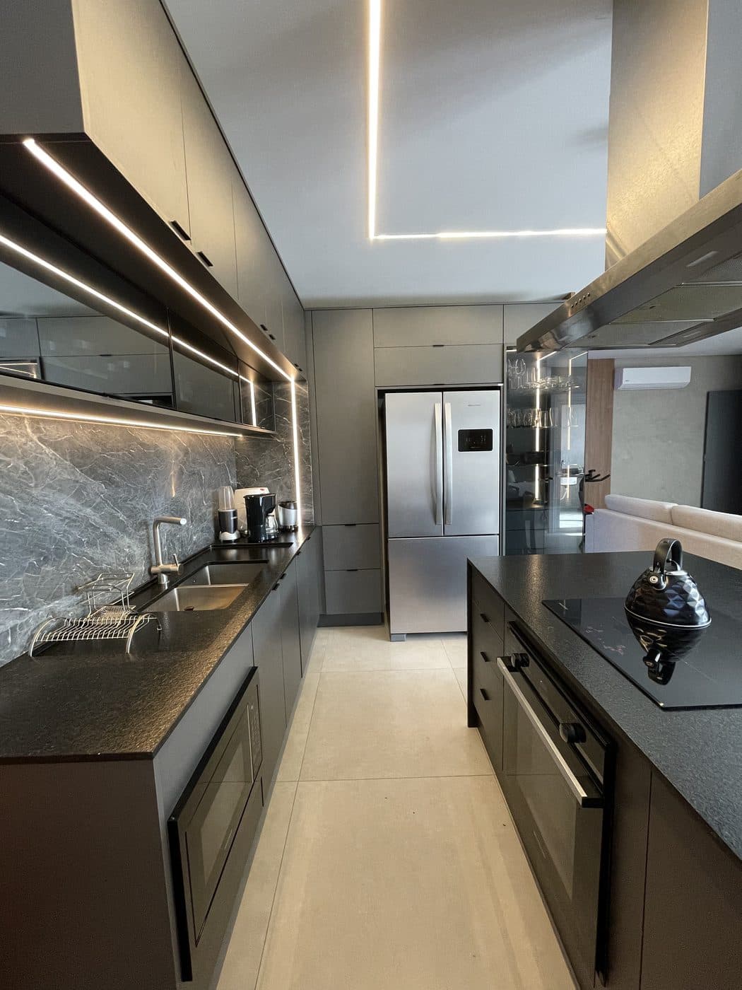 Cozinha planejada da Comar com móveis escuros e iluminação integrada